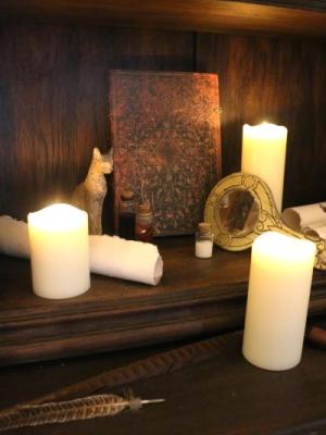 image représentant des bougies, un miroir, des fioles et une statuette de chat