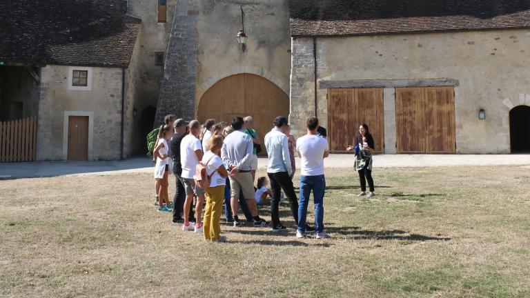 Un groupe de visiteurs suivent une visite guidée dans la cour du château